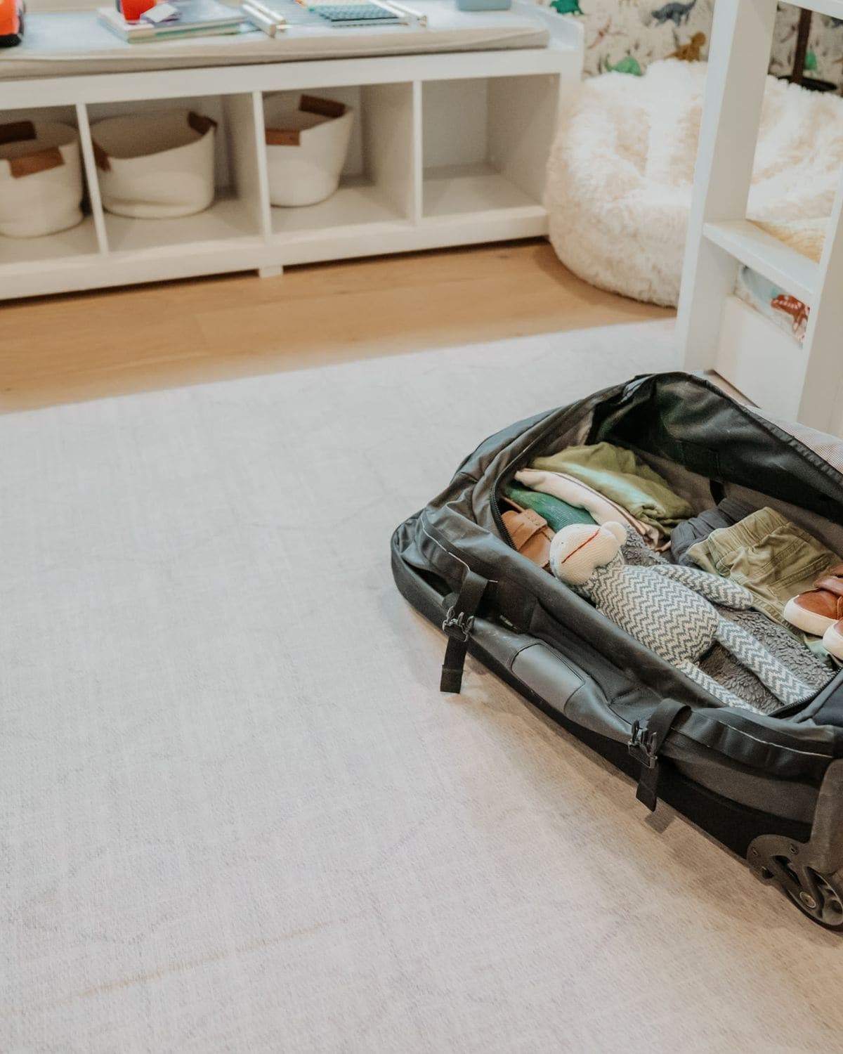 A packed travel bag open on a child's bedroom floor