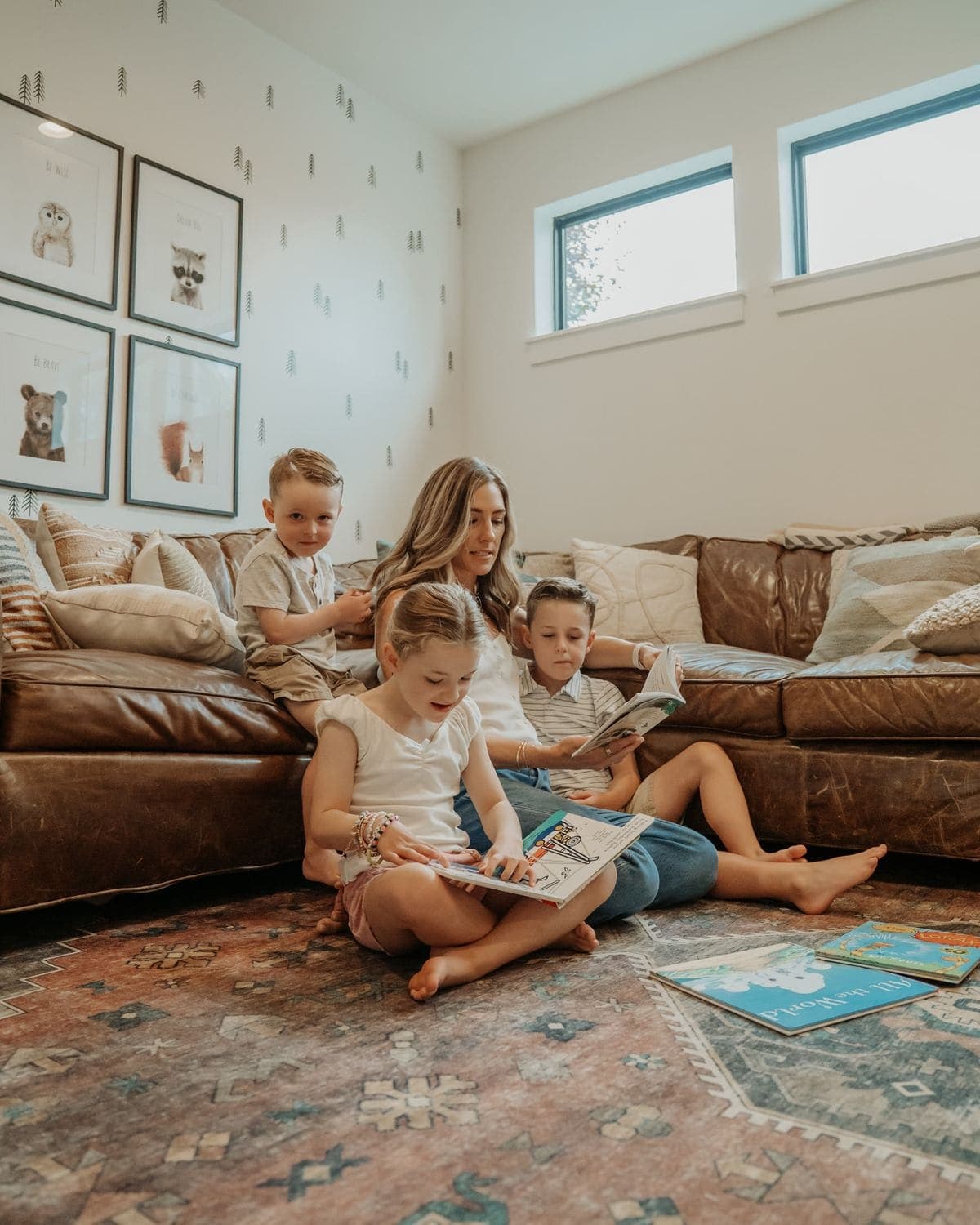 A parent reading picture books with three children on the playroom floor